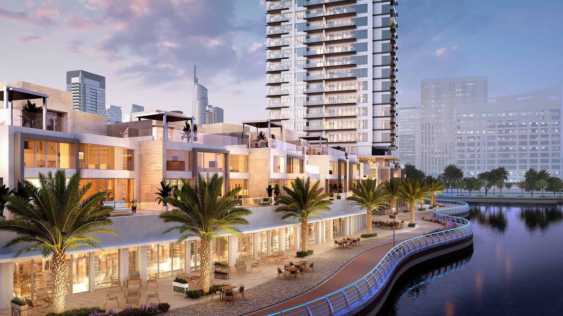 Render of the villas at LIV Waterside in Dubai Marina at dusk, lit terraces above a palm-lined promenade with cafe seating by the water