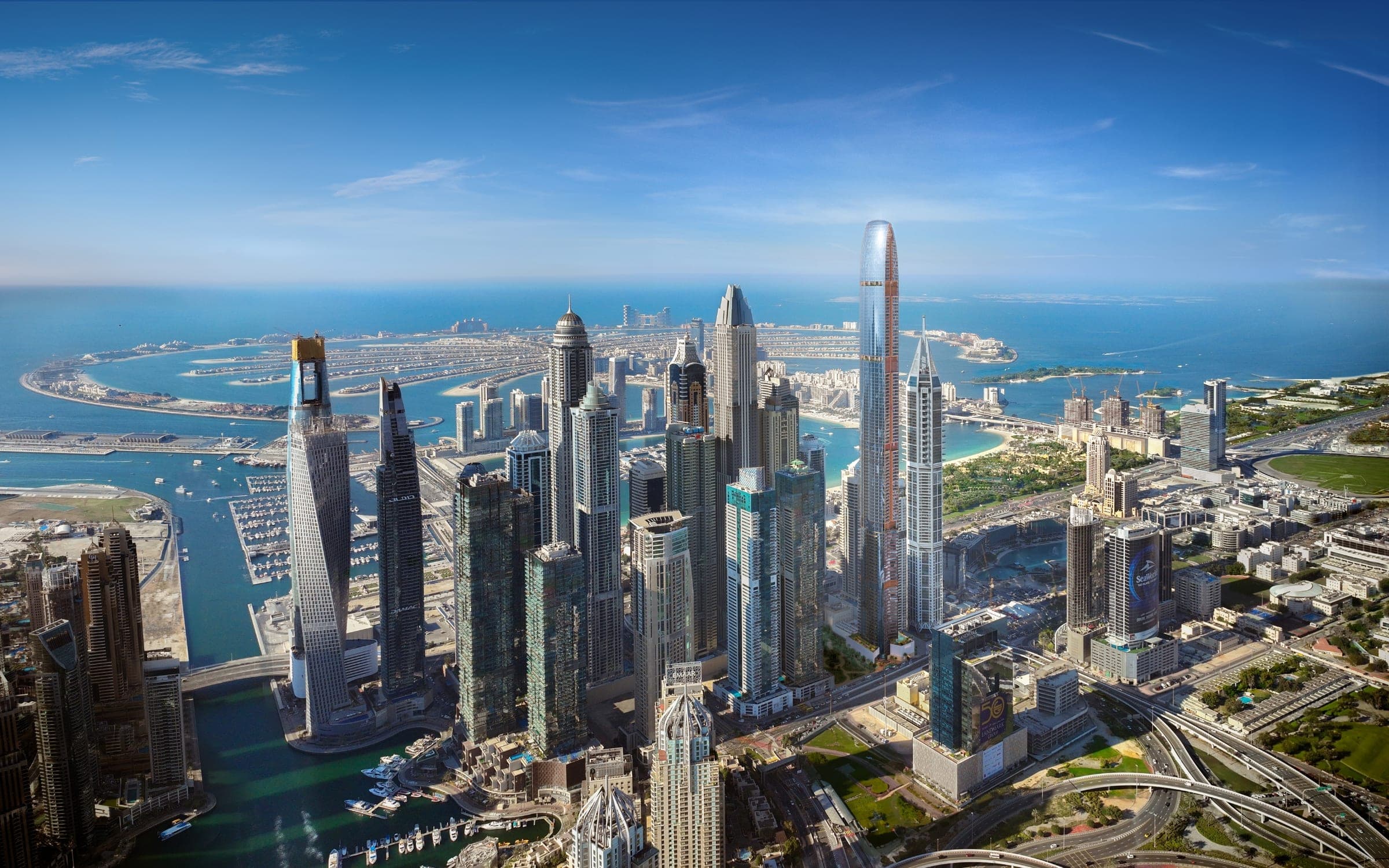 Render of Dubai Marina from the air with the tall Six Senses Residences tower among the marina towers and Palm Jumeirah behind
